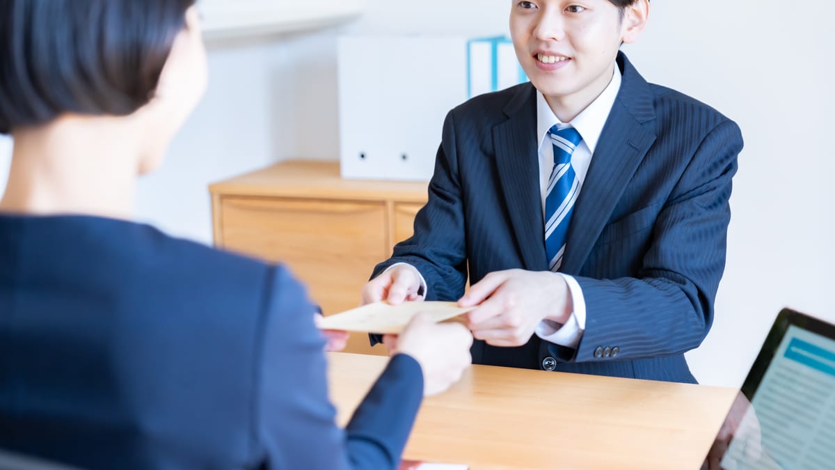 デスク越しに、書類を受け渡すイメージ